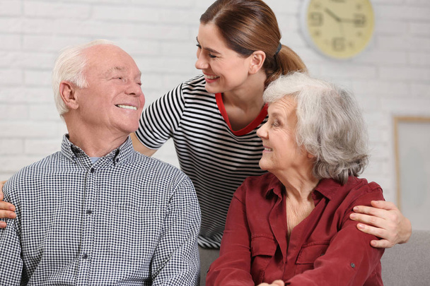 Elderly couple with female caregiver at home - Foto, Imagen