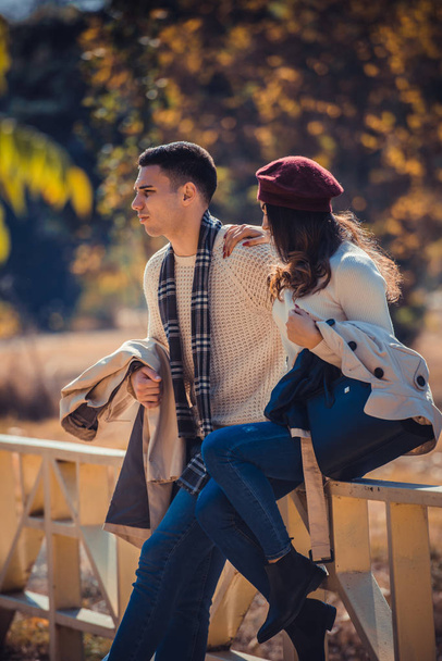 Nádherný pár sedí na mostě v parku a těší podzimní den společně - Fotografie, Obrázek