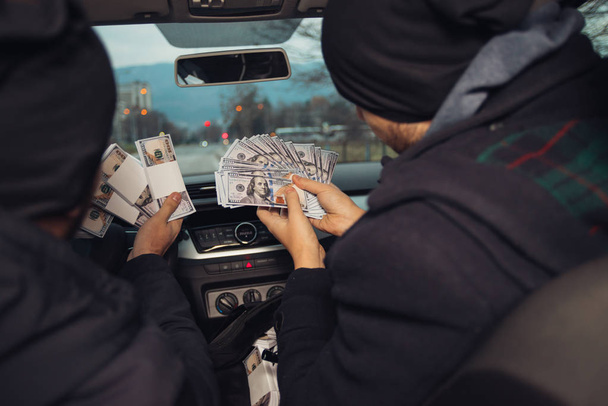 Dos ladrones de bancos felices celebrando su éxito mientras estaban sentados en el coche que utilizaron para el robo. - Foto, imagen
