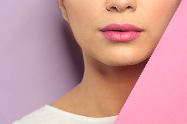 Young woman wearing beautiful lipstick on color background, closeup - Photo, Image