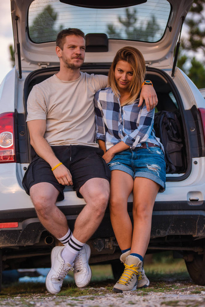 Nuori pari istuu maastoauton takana ja nauttii näkymästä kaikkien maastoajoneuvojen sisältä auringonlaskun aikaan.
. - Valokuva, kuva