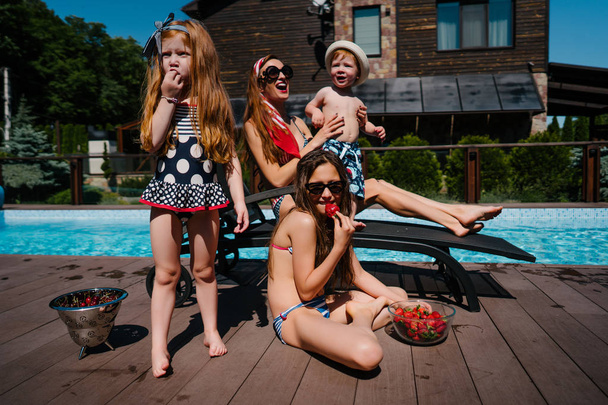 Μια όμορφη οικογένεια είναι χαλαρώνοντας δίπλα στην πισίνα - Φωτογραφία, εικόνα