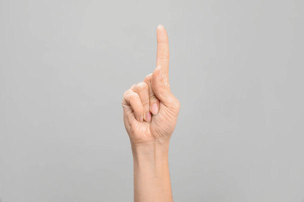 Woman showing number one on grey background, closeup. Sign language - Foto, Imagen