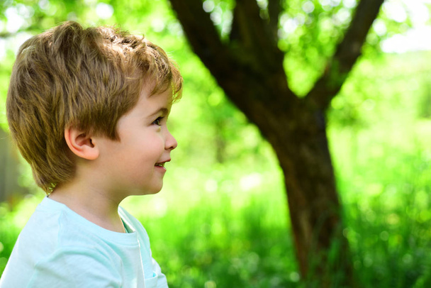 Dziecko na tle zieleni. Wiosna i radość. Mały chłopiec wygląda odległości. Portret. Alergii i pyłkowicy. Piękne dziecko twarzy. - Zdjęcie, obraz