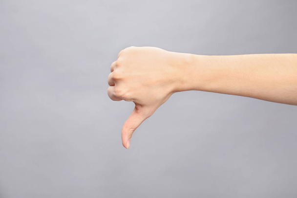 Woman showing thumb down sign on grey background, closeup. Body language - 写真・画像