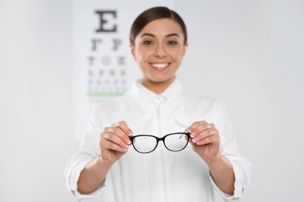 Female ophthalmologist with new eyeglasses in clinic - Фото, зображення