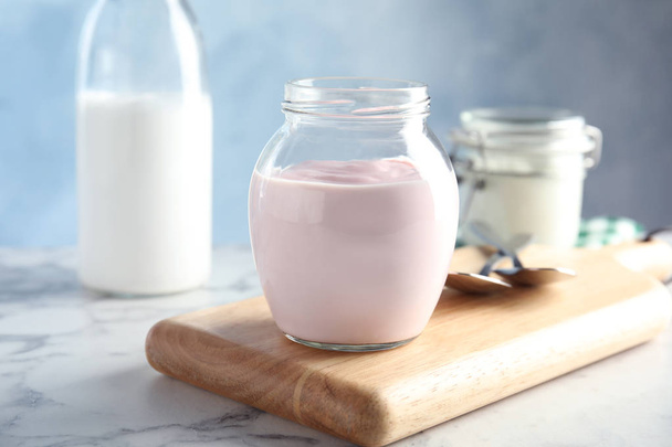 Glass jar of fresh yogurt on table - Foto, imagen