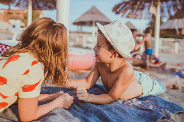 Boldog pozitív gyermekek szórakozás fekve egy törülközőt a strandon - Fotó, kép
