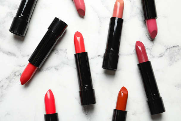 Different lipsticks on marble background, flat lay - Фото, изображение