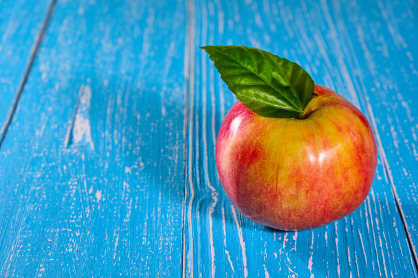Red apple on blue wooden background, copyspace - Fotó, kép