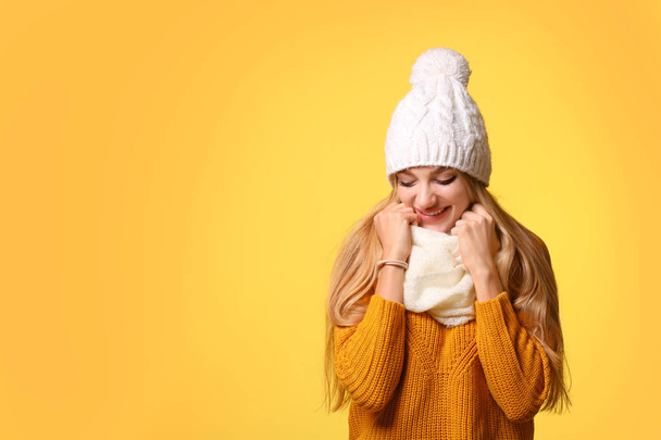 Portrait of emotional young woman in stylish hat, sweater and scarf on color background, space for text. Winter atmosphere - Foto, Imagem