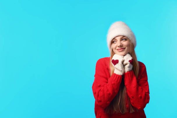 Portrait of emotional young woman in stylish hat, sweater and mittens on color background, space for text. Winter atmosphere - Fotografie, Obrázek