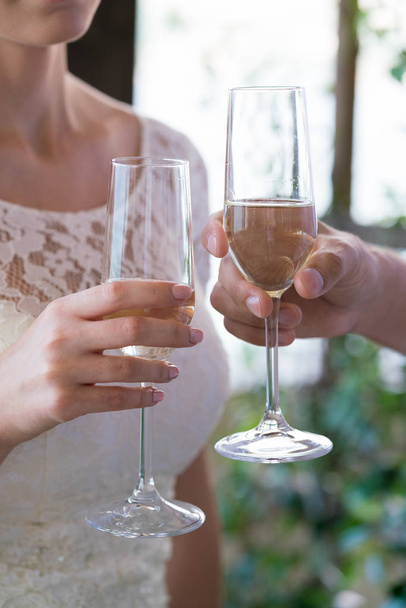 newlyweds are holding champagne glasses and clink glasses - 写真・画像