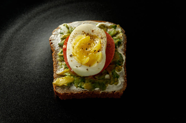 sandwich on black background. bread, egg, tomato, avocado. - Foto, Imagem