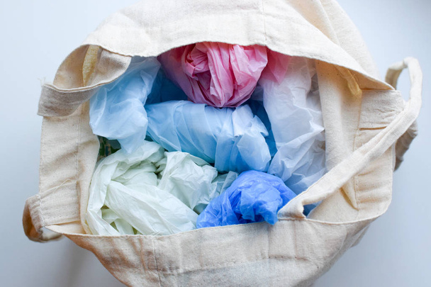 Multi-colored blue, red, white plastic bags in a rag cotton bag - Fotó, kép