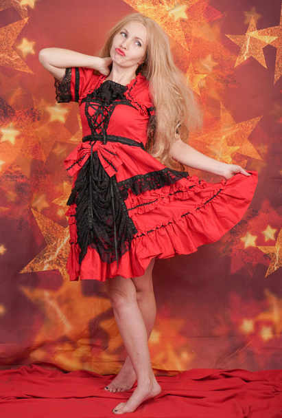 pretty blonde girl in red fairytale dress standing on orange background with stars - Foto, immagini