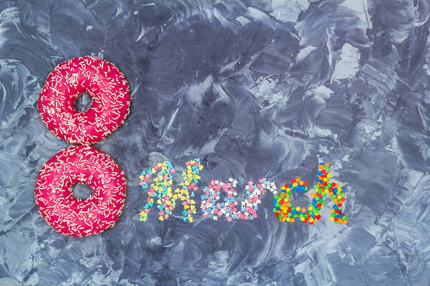 Donuts in Form einer Figur 8 und das Wort Marsch aus dem Konfekt. Ernährungskonzept zum Frauentag. - Foto, Bild