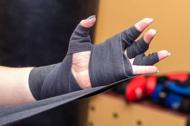 Woman is wrapping hands with grey boxing wraps. Closeup. - Photo, Image