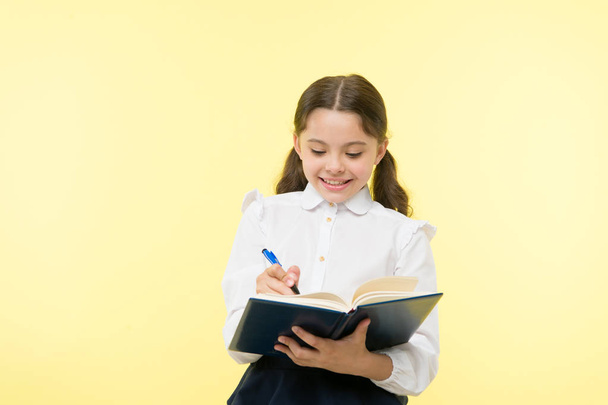 Making notes. Child school uniform kid doing homework. Child girl school uniform clothes hold book and pen. Girl cute write down idea notes. Notes to remember. Write essay or notes. Personal schedule - Φωτογραφία, εικόνα