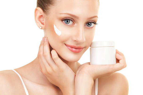 Cute woman applying cream to her face. Care for beautiful woman skin. Cosmetology, spa therapy and makeup at beauty salon. Closeup portrait of woman face with cream - Valokuva, kuva