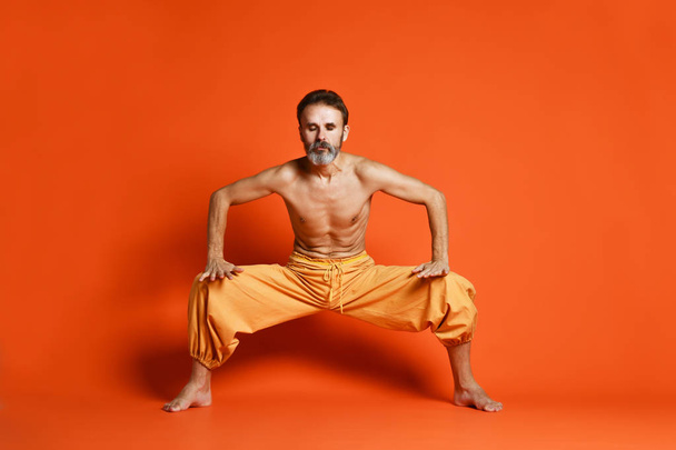 Portrait of yogi men doing yoga exercise on black mat, he breath and performing Upward abdominal lock, Uddiyana Bandha. - 写真・画像