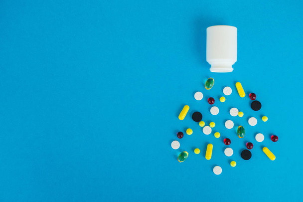 Ιατρική χαπιών. Χρωματιστά χάπια και κάψουλα σε μπλε φόντο. Φαρμακείο θέμα, καψάκιο χάπια με αντιβιοτικό φάρμακο στα πακέτα - Φωτογραφία, εικόνα