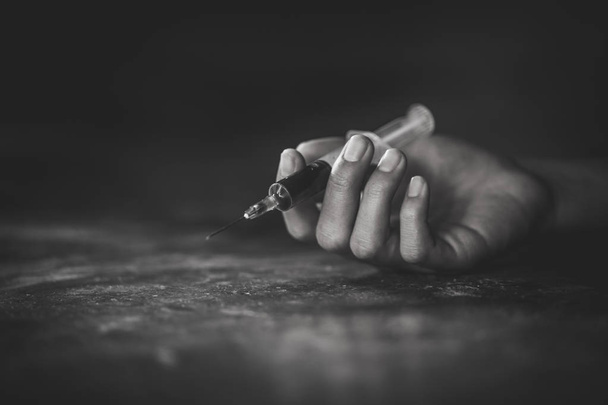 Main de femme d'un toxicomane et une seringue avec seringue narcotique couchée sur le sol, Surdosage, concept de drogue
. - Photo, image
