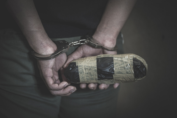 Traficante de drogas bajo arresto confinado con esposas junto con heroína, Ley y concepto policial. Día Mundial contra la Droga
 - Foto, Imagen