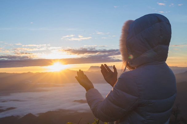 Morgengebet, Frau betet mit den Händen zusammen auf dem Hintergrund des morgendlichen Sonnenaufgangs. - Foto, Bild
