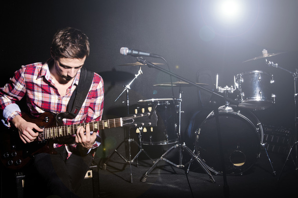 Человек играет на гитаре во время концерта
 - Фото, изображение