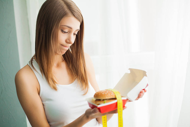 Diet. Woman with guilty feeling to eat a hamburger - Photo, Image
