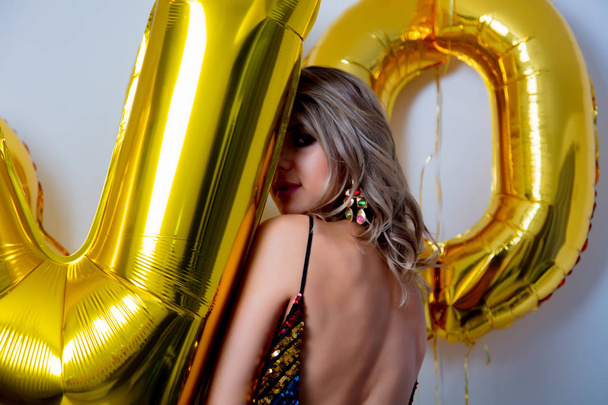 Młoda kobieta z golden balony na jej urodziny trzydzieści lat. Wewnątrz budynku. Osoba jest w vintage 80-strój i fryzurę. Na białym tle - Zdjęcie, obraz