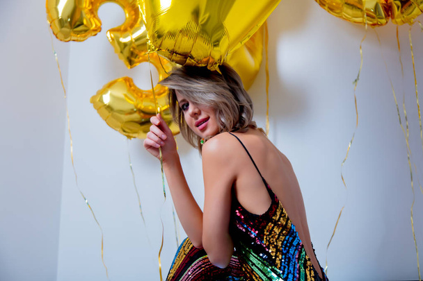 Jonge vrouw met gouden ballonnen op haar verjaardag van dertig jaar. Overdekte locatie. Persoon is in vintage 80ste jurk en kapsel. Op witte achtergrond - Foto, afbeelding