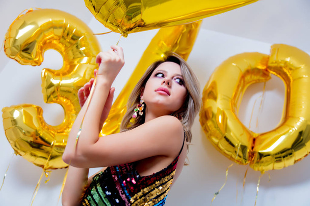 Young woman with golden balloons on her thirty years birthday. Indoor location. Person is in vintage 80th dress and hairstyle. On white background - Foto, immagini