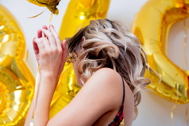 Mujer joven con globos dorados en sus treinta años de cumpleaños. Ubicación interior. Persona está en la vendimia 80º vestido y peinado. Sobre fondo blanco
 - Foto, Imagen
