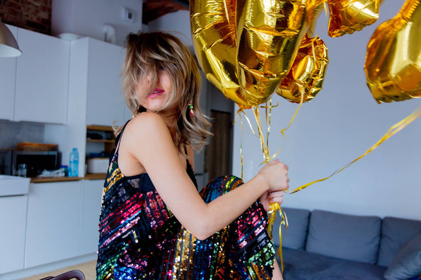 Young woman with golden balloons on her thirty years birthday. Indoor location. Person is in vintage 80th dress and hairstyle. At home  - Valokuva, kuva