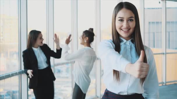 Face of a handsome young cheerful smiling business woman. Showing a gesture class against the background of colleagues sincerely smiles with copy space - Footage, Video