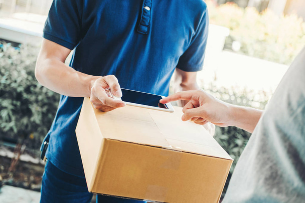Customer Man signature in Smart Phone to receive package from professional delivery man at home - 写真・画像