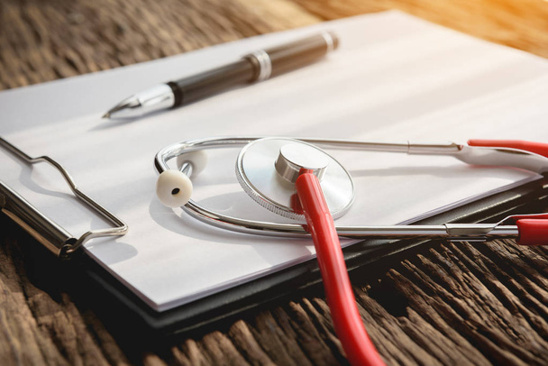 doctor workplace with stethoscope and clipboard at wooden desk, health background concepts. - Fotó, kép