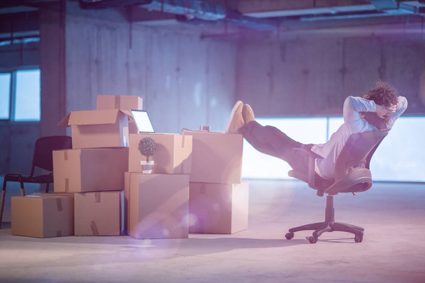 young businessman on construction site taking a break while checking documents and business workflow with cardboard boxes around him in new startup office - Foto, imagen