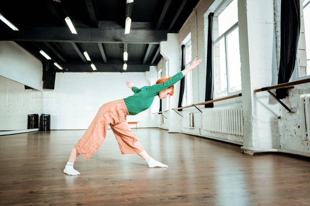Pleasant-looking fit yoga instructor in a green turtleneck doing asana for stretching - Valokuva, kuva