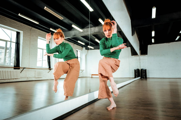 Krásné profesionální moderní tanečnice s červenými vlasy tančí u zrcadla - Fotografie, Obrázek
