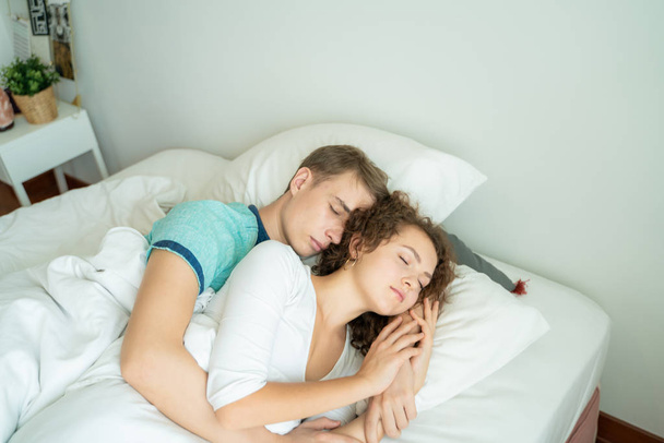 Beautiful young man and women love couple hugging on bed in morning - Foto, imagen