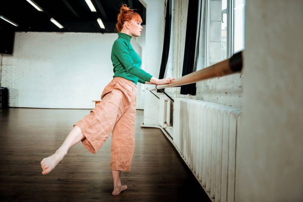 Young professional ballet dancer with hair bun doing pas - Fotoğraf, Görsel