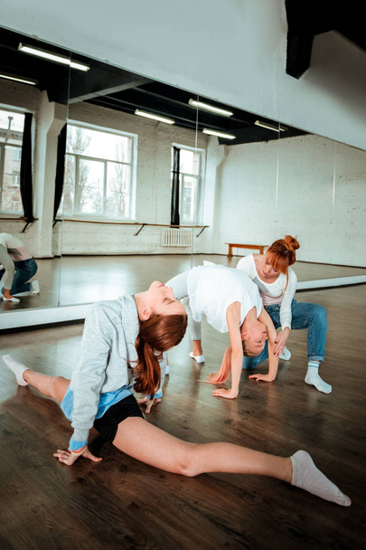 Two teenagers from generation z and their teacher having a gymnastics workout in the studio - Zdjęcie, obraz