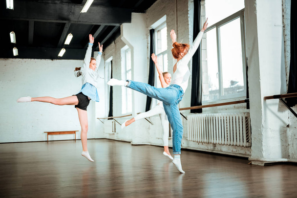 Red-haired dance teacher in blue jeans and her students doing leg swing - Foto, Imagem
