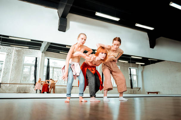 Beautiful dance teacher with red hair and her students looking serious - 写真・画像