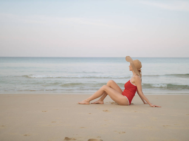 Szczęśliwa kobieta podróżnik w czerwony strój kąpielowy i kapelusz relaks na plaży - Zdjęcie, obraz