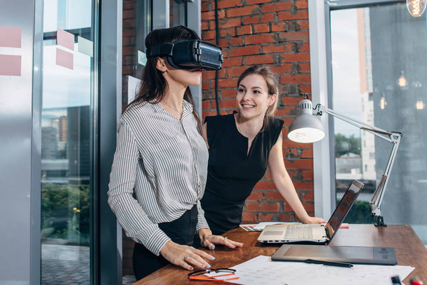 Dos desarrolladores de aplicaciones femeninas prueban una nueva aplicación diseñada para auriculares VR de pie en la oficina moderna
 - Foto, Imagen