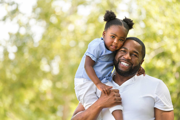 Отец афроамериканец обнимает и держит свою маленькую девочку
. - Фото, изображение